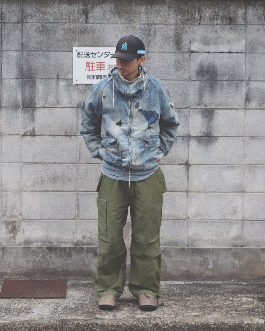 フラップポケットや膝のタック、裾のドローコードなど、ミリタリーディテールを随所に取り入れた1本。通常は内側に配置されるポケットをあえて外側に設けたカーゴポケットが印象的です。ムラ糸で織り上げたバックサテン生地は、独特のハリとコシを持ち、深みのあるオリーブカラーが魅力です。