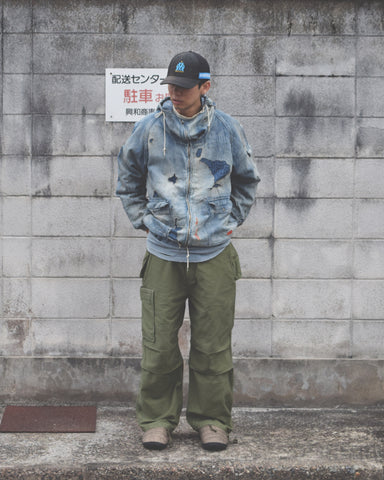 フラップポケットや膝のタック、裾のドローコードなど、ミリタリーディテールを随所に取り入れた1本。通常は内側に配置されるポケットをあえて外側に設けたカーゴポケットが印象的です。ムラ糸で織り上げたバックサテン生地は、独特のハリとコシを持ち、深みのあるオリーブカラーが魅力です。