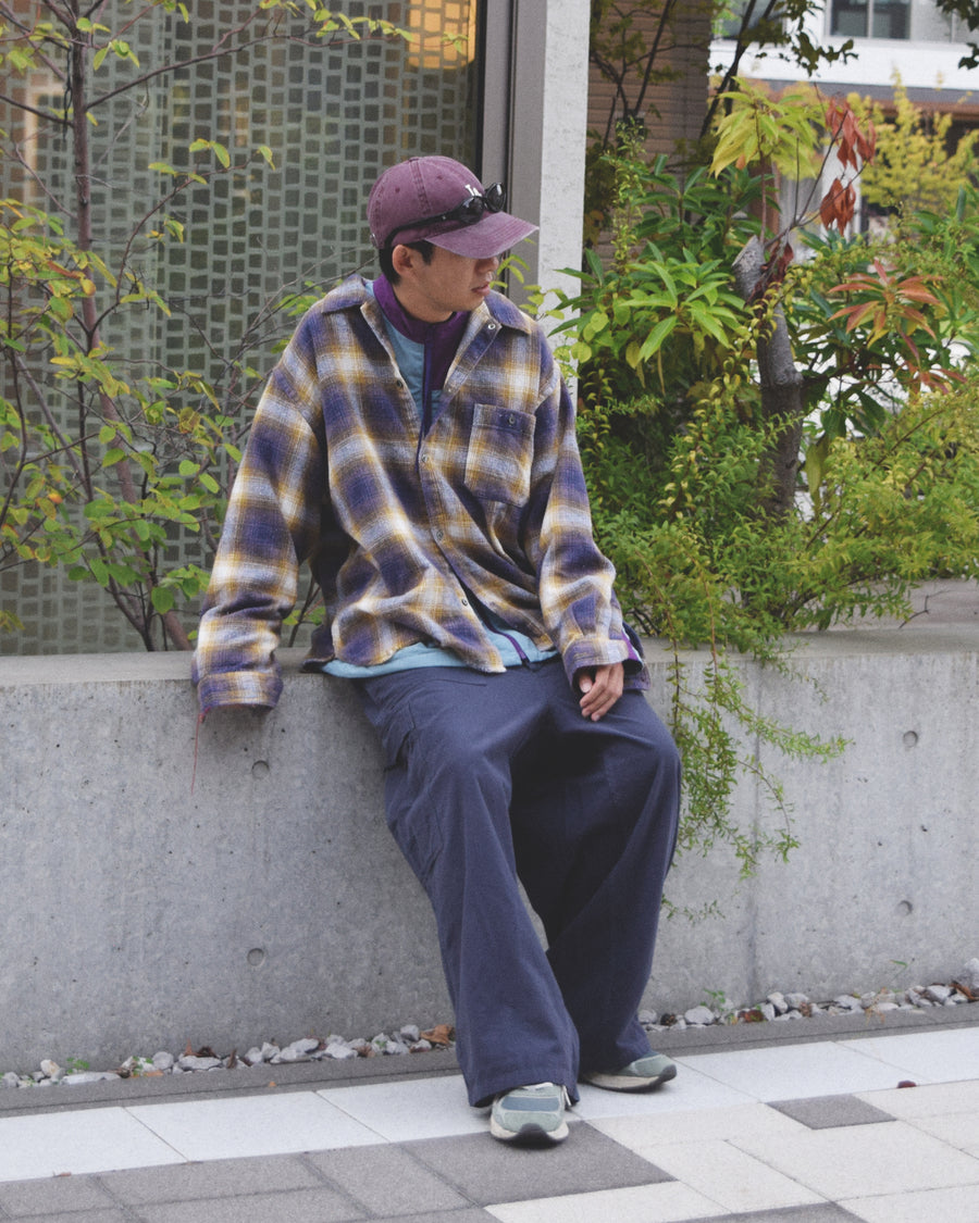 ANACHRONORMで以前リリースしていたリサイズシャツのシルエットをリファインした、ワイドシルエットシャツです。
随所に施された細かなステッチワークやダメージ加工にもご注目ください。
生地はリサイクルコットンとポリエステルを混紡したT/Cネップチェックで、起毛によるネップの風合いとメランジ染めの独特なムラ感が特徴です。
使用している生地はバランス別注でパープルとイエローのチェック柄。
サスティナブルブリーチ加工とダメージ加工を施しており、環境に配慮しつつPURPLE×BLACKカラーで仕上げています。