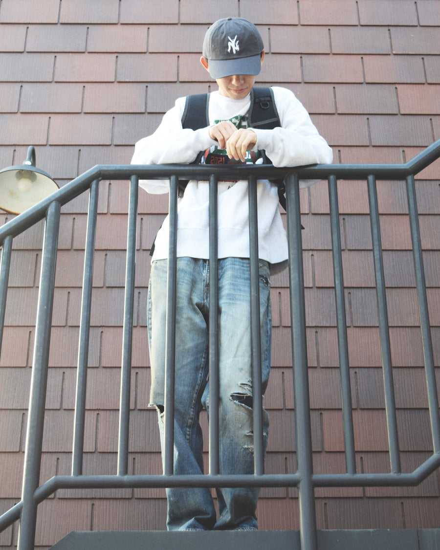 1985年のLEVIS 550をベースに再構築した、ワイドテーパードのリメイク5Pデニム。
12.5ozデニムのタテ糸には中白のインディゴロープ染色糸を使用し、ムラ感のある豊かな表情を演出。タテ落ちとインディゴの濃淡を活かすことで、ヴィンテージにはない独自の風合いを表現しています。さらに手作業のトーンコントロールと特別なエイジング加工を加えることで奥行きある仕上がりに。オリジナル染料の吹き付けにより、モダンでソリッドな印象も併せ持つ一本です。This remade 5P denim features a wide tapered silhouette inspired by the 1985 LEVIS 550.
The 12.5oz denim uses medium-white indigo rope–dyed warp yarns, giving it a textured, slubby character.
By highlighting vertical fading and vivid indigo variations, it achieves a look distinct from vin