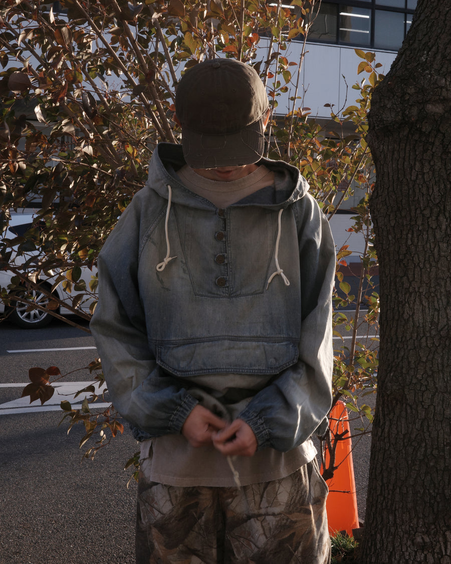 フード口のボタンの開閉により、首まわりのニュアンスを変えて楽しめる一着。素材には、経糸にコットンムラ糸、緯糸に綿麻混紡糸を使用した綿麻6ozデニムを採用しました。シャープなムラ感とリネン混ならではの粗野な風合いが、ヴィンテージの魅力を引き立てます。エイジング加工を施すことで、全体にリアリティのあるアタリ感を出し、長年着込んだような深みのある表情に仕上げました。A versatile piece featuring adjustable hood buttons to create a clean or relaxed neckline. Crafted from 6oz cotton-linen denim, the fabric combines sharp slub textures with a rustic linen feel for an authentic vintage character. Treated with an aging process to create realistic wear and fade, this INDIGO garment offers a sophisti