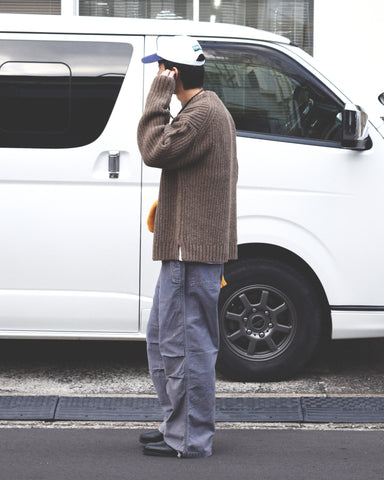 フラップポケットや膝のタック、裾のドローコードなど、ミリタリーのディテールをふんだんに取り入れた一本。内側に配置されることの多いポケットをあえて外側に設けたカーゴポケットが特徴です。ムラ糸で織り上げたバックサテン生地は、ハリとコシのある質感が魅力。さらに、水や薬品の使用を抑えながら生地の凹凸を際立たせる特殊エイジング加工を施し、深みのあるネイビーカラーに仕上げています。