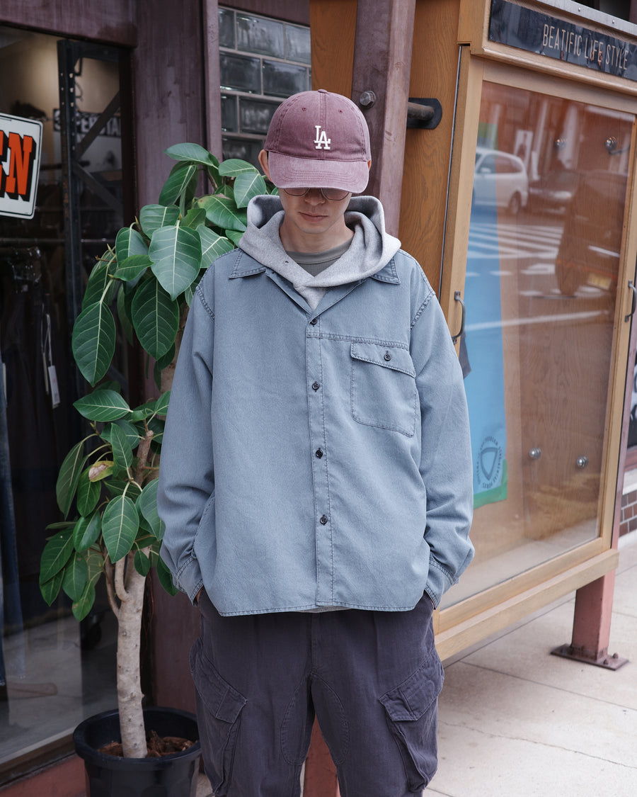 ポリエステル100％ながら、綿のような質感と軽量性を備えた高機能素材を採用。タスラン加工糸を使用したポリエステルオックスは、シワになりにくく速乾性にも優れています。本来染色が困難な素材に特殊顔料染めを施すことで、化繊特有の光沢を抑え、ナチュラルで奥行きのある絶妙なフェード感と落ち着いた表情を実現しました。

A high-performance piece crafted from polyester oxford, offering a cotton-like touch with quick-dry and wrinkle-resistant benefits. This GRAY BLUE item features a special pigment dye—a rare process for polyester—achieving a sophisticated, faded texture and a matte finish that perfectly balances technical utility with a natural, lived-in aesthetic.