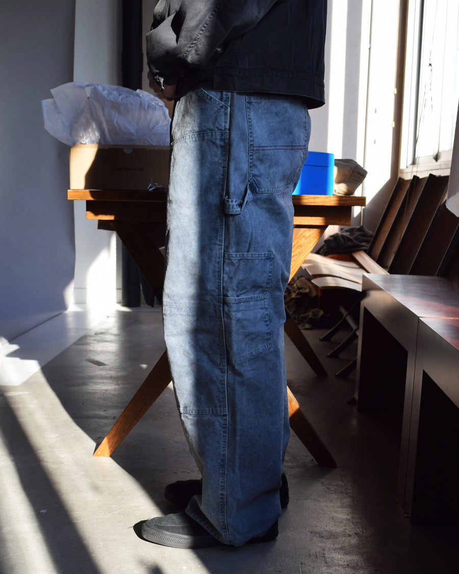 通年着用できるスタンダードなペインターパンツ。ややワイドで長めに設定したレングスは、ミリ単位の調整により絶妙なバランスに仕上げました。素材には強度と耐久性に優れた8号帆布を採用。特殊顔料染めを施すことで、ムラ感のある独自の奥行きと、穿き込むほどにアタリが増す豊かな経年変化を楽しめる一本です。

Standard painter pants designed for year-round wear. The slightly wide, long-length silhouette has been carefully refined for a perfect balance. Crafted from durable No.8 canvas, this BLUE pair features a special pigment dye that creates a unique, mottled depth. The rugged fabric is built to develop a beautiful patina and character over time.