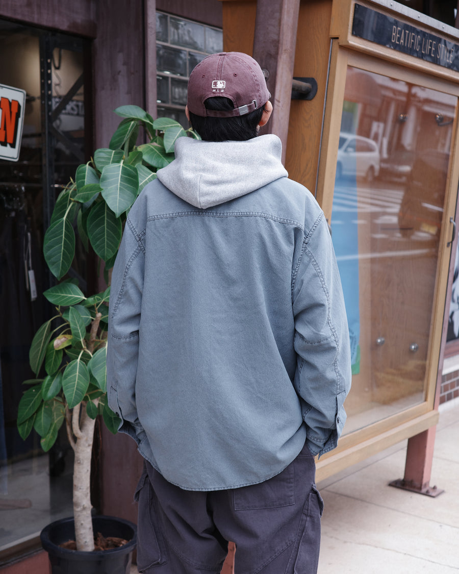 ポリエステル100％ながら、綿のような質感と軽量性を備えた高機能素材を採用。タスラン加工糸を使用したポリエステルオックスは、シワになりにくく速乾性にも優れています。本来染色が困難な素材に特殊顔料染めを施すことで、化繊特有の光沢を抑え、ナチュラルで奥行きのある絶妙なフェード感と落ち着いた表情を実現しました。

A high-performance piece crafted from polyester oxford, offering a cotton-like touch with quick-dry and wrinkle-resistant benefits. This GRAY BLUE item features a special pigment dye—a rare process for polyester—achieving a sophisticated, faded texture and a matte finish that perfectly balances technical utility with a natural, lived-in aesthetic.