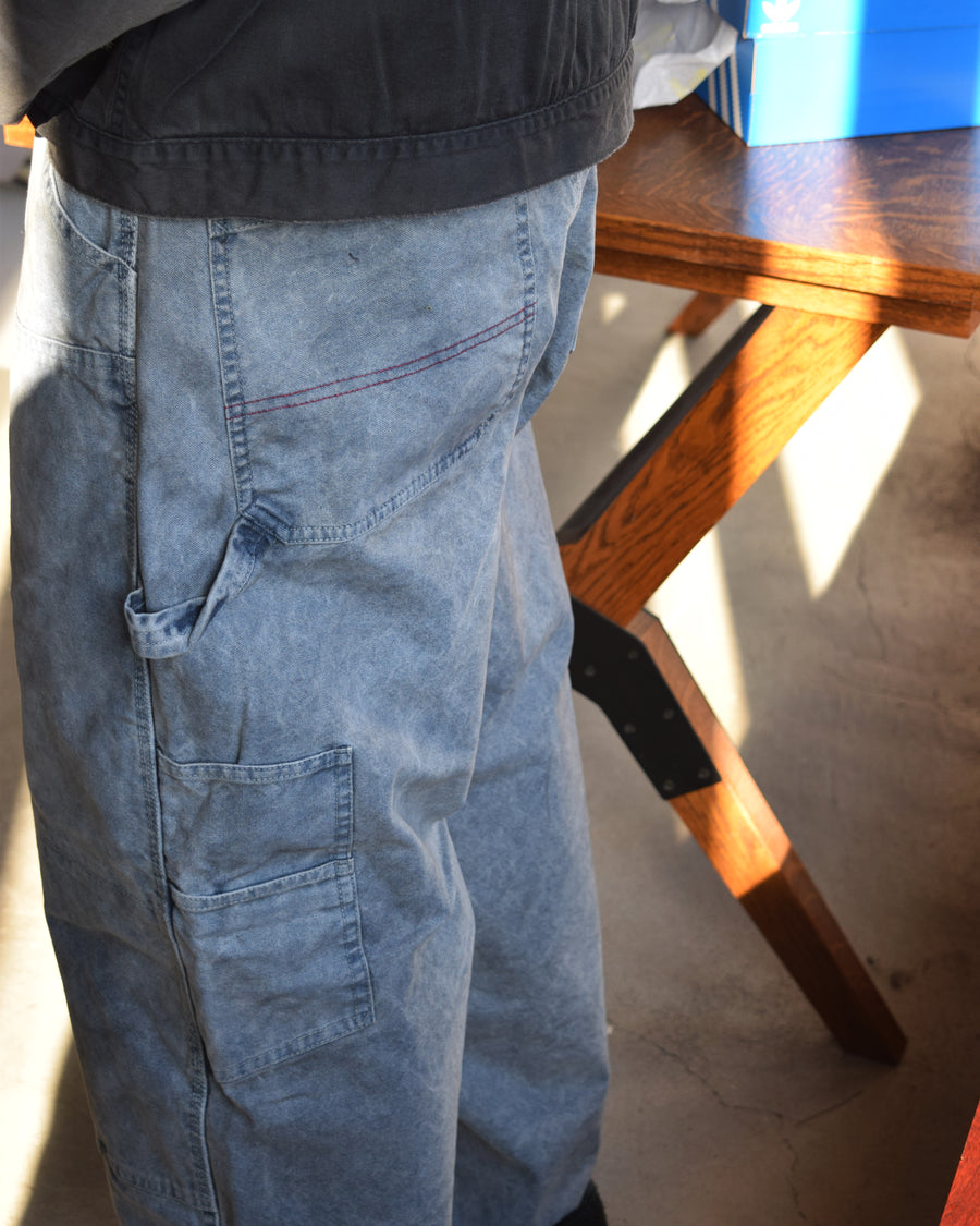 通年着用できるスタンダードなペインターパンツ。ややワイドで長めに設定したレングスは、ミリ単位の調整により絶妙なバランスに仕上げました。素材には強度と耐久性に優れた8号帆布を採用。特殊顔料染めを施すことで、ムラ感のある独自の奥行きと、穿き込むほどにアタリが増す豊かな経年変化を楽しめる一本です。

Standard painter pants designed for year-round wear. The slightly wide, long-length silhouette has been carefully refined for a perfect balance. Crafted from durable No.8 canvas, this BLUE pair features a special pigment dye that creates a unique, mottled depth. The rugged fabric is built to develop a beautiful patina and character over time.