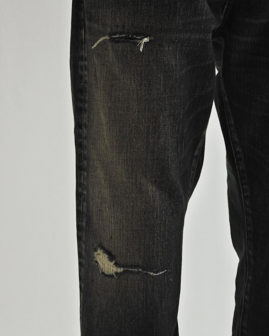 ANACHRONORM定番のレギュラーテーパード5Pパンツをベースに、リメイクで再構築した一本。
腰回りにはゆとりを持たせつつ、裾へ向かってすっきりと収まる美しいテーパードシルエットが特徴です。
タテ糸は硫化ロープ染色を施した芯白仕様で、ブラックからグレーへ自然にフェードする豊かな経年変化が魅力。
ムラ糸が生み出す自然な陰影により、ヴィンテージライクな表情を楽しめます。
さらにタテヨコに硫化ブラックのスラブ糸を使用し、ベーストーンを抑えながらもアタリを際立たせた奥行きのあるコントラストを表現。
リアルなユーズド感を備えた、加工映えする一本に仕上げています。
A reconstructed take on ANACHRONORM’s classic Regular Tapered 5P Pants, refined through its remake design.
The fit offers room around the waist with a clean taper toward the hem, ensuring both comfort and sharp lines.
Warp yarns a