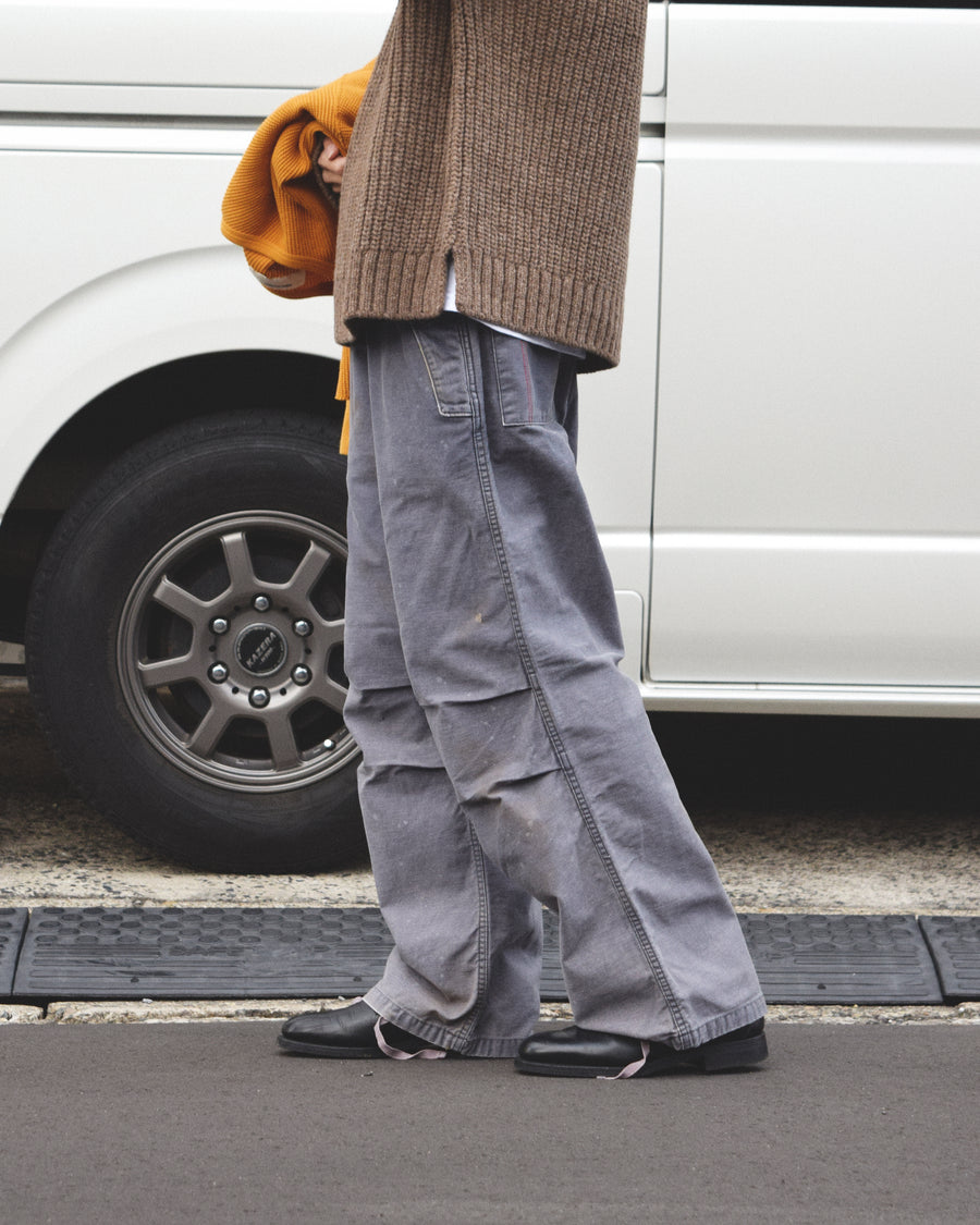 フラップポケットや膝のタック、裾のドローコードなど、ミリタリーのディテールをふんだんに取り入れた一本。内側に配置されることの多いポケットをあえて外側に設けたカーゴポケットが特徴です。ムラ糸で織り上げたバックサテン生地は、ハリとコシのある質感が魅力。さらに、水や薬品の使用を抑えながら生地の凹凸を際立たせる特殊エイジング加工を施し、深みのあるネイビーカラーに仕上げています。