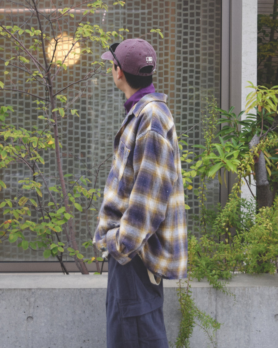 ANACHRONORMで以前リリースしていたリサイズシャツのシルエットをリファインした、ワイドシルエットシャツです。
随所に施された細かなステッチワークやダメージ加工にもご注目ください。
生地はリサイクルコットンとポリエステルを混紡したT/Cネップチェックで、起毛によるネップの風合いとメランジ染めの独特なムラ感が特徴です。
使用している生地はバランス別注でパープルとイエローのチェック柄。
サスティナブルブリーチ加工とダメージ加工を施しており、環境に配慮しつつPURPLE×BLACKカラーで仕上げています。