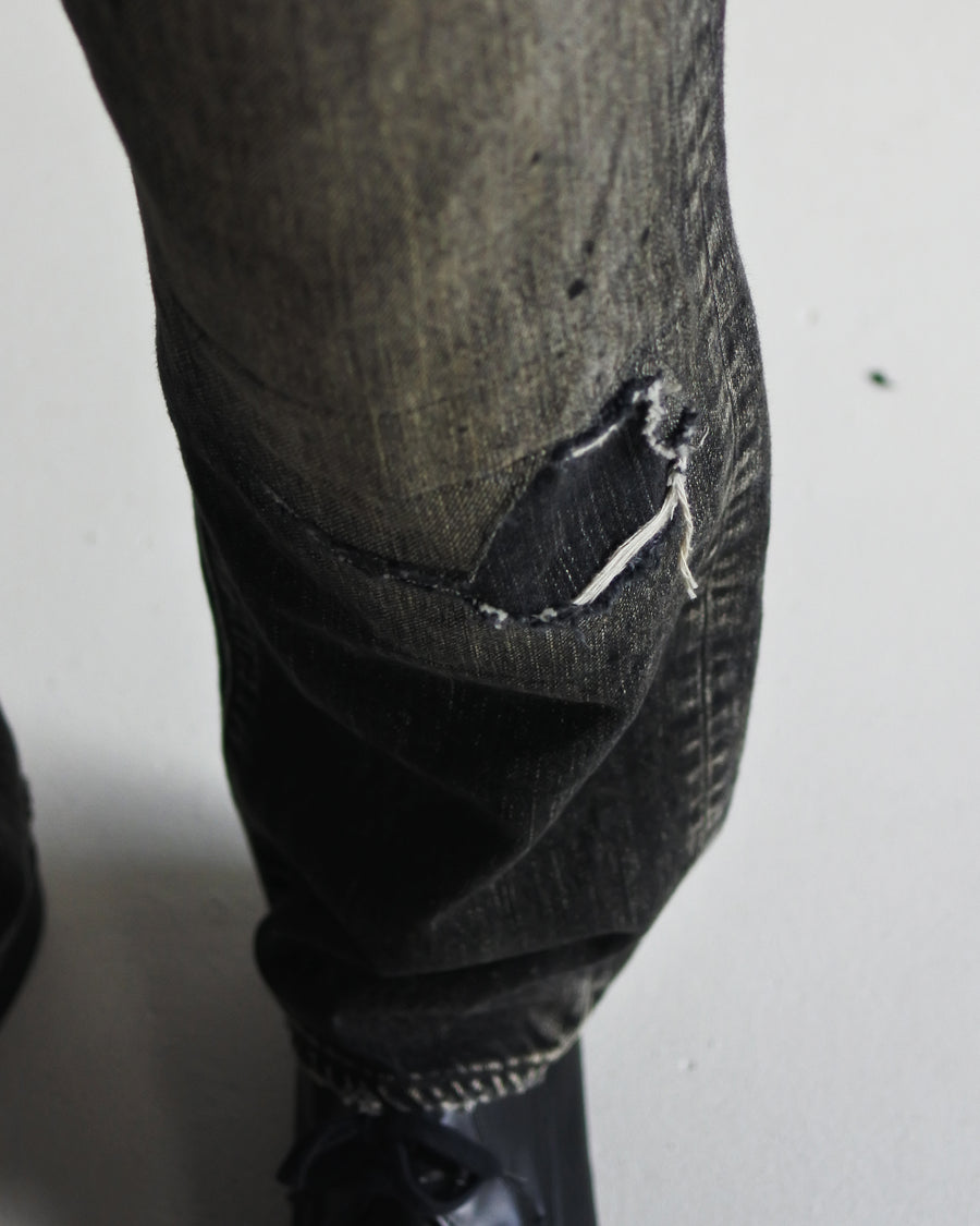 ANACHRONORM定番のレギュラーテーパード5Pパンツをベースに、リメイクで再構築した一本。
腰回りにはゆとりを持たせつつ、裾へ向かってすっきりと収まる美しいテーパードシルエットが特徴です。
タテ糸は硫化ロープ染色を施した芯白仕様で、ブラックからグレーへ自然にフェードする豊かな経年変化が魅力。
ムラ糸が生み出す自然な陰影により、ヴィンテージライクな表情を楽しめます。
さらにタテヨコに硫化ブラックのスラブ糸を使用し、ベーストーンを抑えながらもアタリを際立たせた奥行きのあるコントラストを表現。
リアルなユーズド感を備えた、加工映えする一本に仕上げています。
A reconstructed take on ANACHRONORM’s classic Regular Tapered 5P Pants, refined through its remake design.
The fit offers room around the waist with a clean taper toward the hem, ensuring both comfort and sharp lines.
Warp yarns a