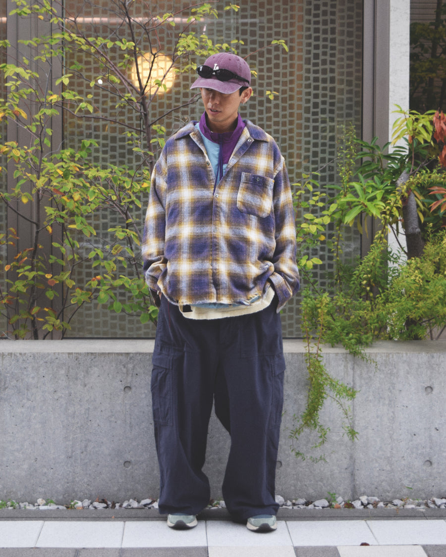 ANACHRONORMで以前リリースしていたリサイズシャツのシルエットをリファインした、ワイドシルエットシャツです。
随所に施された細かなステッチワークやダメージ加工にもご注目ください。
生地はリサイクルコットンとポリエステルを混紡したT/Cネップチェックで、起毛によるネップの風合いとメランジ染めの独特なムラ感が特徴です。
使用している生地はバランス別注でパープルとイエローのチェック柄。
サスティナブルブリーチ加工とダメージ加工を施しており、環境に配慮しつつPURPLE×BLACKカラーで仕上げています。