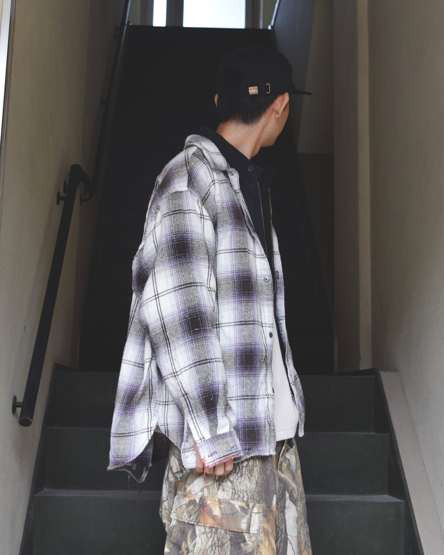 ANACHRONORMで以前リリースしていたリサイズシャツのシルエットをリファインした、ワイドシルエットシャツです。
随所に施された細かなステッチワークやダメージ加工にもご注目ください。
生地はリサイクルコットンとポリエステルを混紡したT/Cネップチェックで、起毛によるネップの風合いとメランジ染めの独特なムラ感が特徴です。
サスティナブルブリーチ加工とダメージ加工を施しており、環境に配慮しつつPURPLE×BLACKカラーで仕上げています。