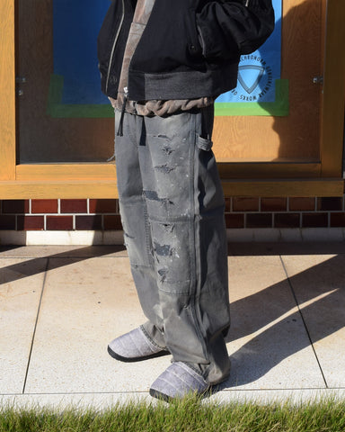 【 商品名：リメイクダブルニーダックペインターパンツ 】

本製品は、レングスをやや長めに設定したブラックカラーのペインターパンツです。ウエスト部分にはナイロンオックス生地で切り替えを施し、ワーク感を抑えつつバランスの良いデザインに仕上げています。生地には頒布の中でも最も薄手の11号帆布生地を使用しており、強度・耐久性に優れるだけでなく、着用を重ねるごとにアタリなどの経年変化を楽しめる素材です。また、水や薬品の使用量を抑えながら生地の凹凸部分のアタリを強調し、同時に自然な脱色感を与える特殊エイジング加工に加え、サンフェードによるダメージ加工も施すことで、より味わい深い表情に仕上げています。