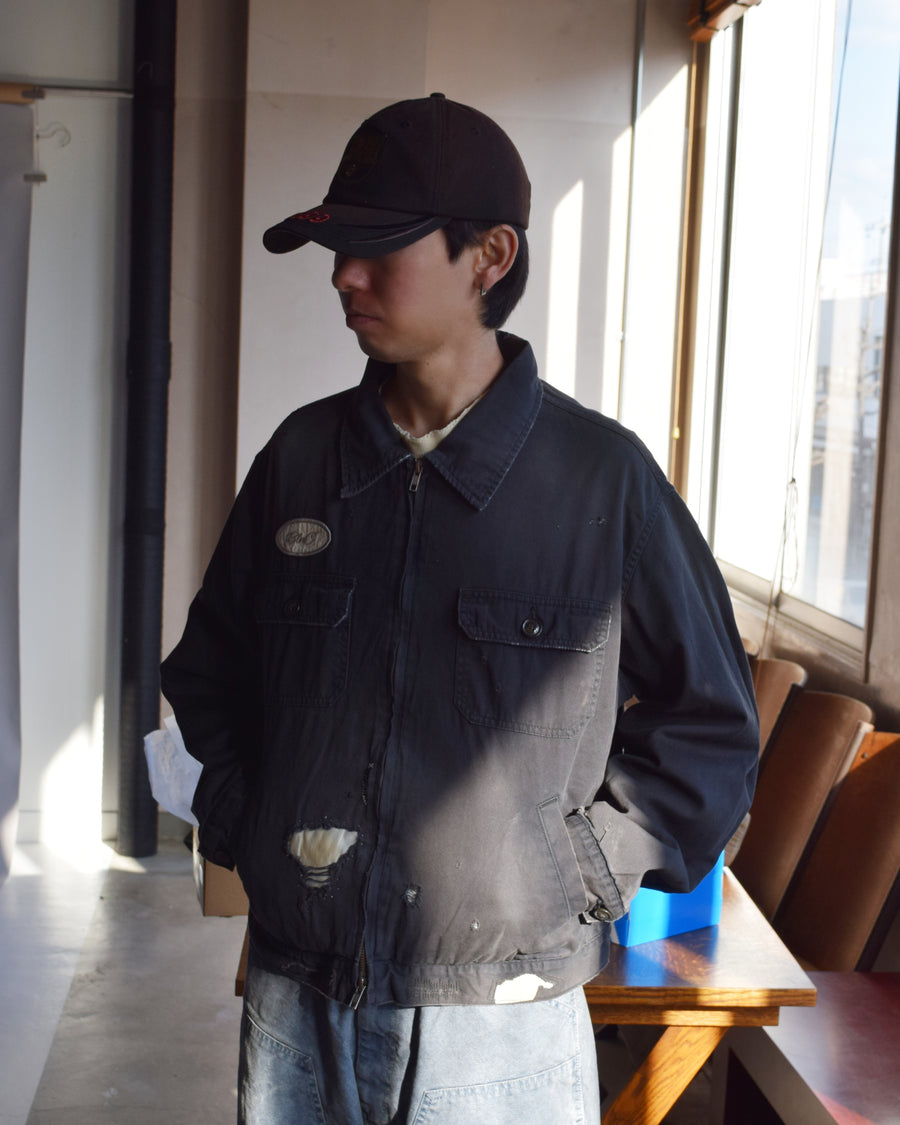 ヴィンテージのワークジャケットを現代的シルエットで再現。柔らかくコシのある20番手ツイルに、環境負荷を抑えた特殊エイジング・サンフェード加工、さらにダメージ加工を施すことで、長年着込んだようなリアルな色落ちと風合いを忠実に表現しました。裏地には高密度なコットンスレーキを採用。鮮やかなブラックのボディに、オリジナルワッペンがアクセントを添える、ヴィンテージ感溢れる一着です。
A modern reimagining of the classic vintage work jacket. Made from soft 20s twill and treated with a special sun-fade and damage process for a realistic, time-worn look. This BLACK jacket features high-density lining and original custom patches, creating a unique, heritage-inspired finish with authentic distressing.