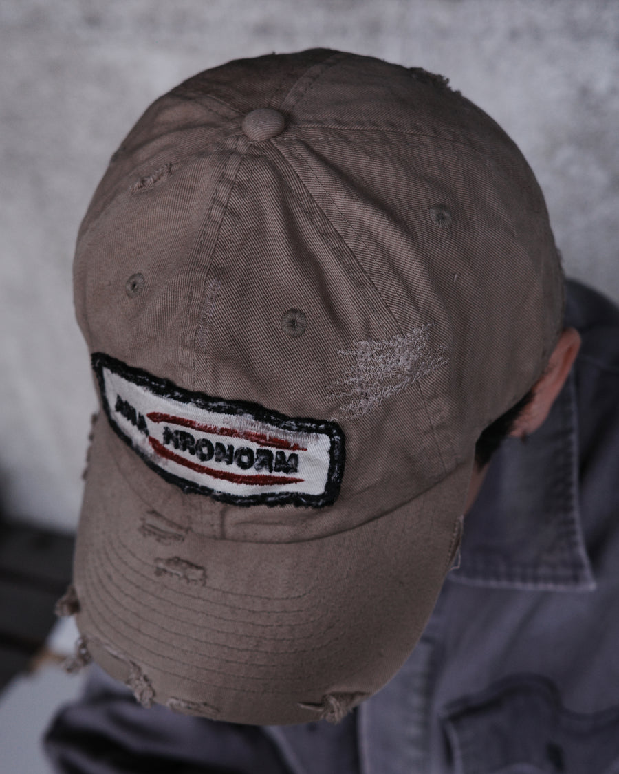 ダメージ加工とステッチ補強で、長年使い込まれた風合いを表現したキャップ。オリジナルワッペンにも同様の加工を施し、全体の統一感を高めました。素材には先染めのピグメントコットンキャンバスを採用。実用性とヴィンテージな佇まいを兼ね備え、スタイリングにこなれたアクセントを添える一着に仕上げています。

A distressed cap featuring reinforced stitching for a rugged, time-worn look. Both the body and the original patch are meticulously aged for a cohesive vintage aesthetic. Crafted from pre-dyed pigment cotton canvas, this BEIGE piece combines durability with a sophisticated, lived-in feel, perfect for adding character to any outfit.