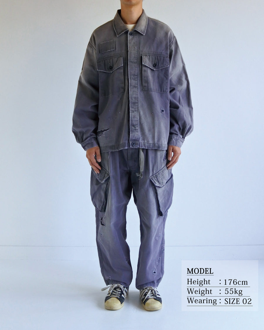 ミリタリーのシャツジャケットを現代的シルエットに更新。裾のドローコードでスタイルに合わせた変化を楽しめます。素材には肌馴染みの良い10sヘリンボンを採用。環境に配慮した特殊エイジング・サンフェード加工とダメージ加工を施すことで、クラシカルな生地にリアリティのある褪色感とヴィンテージライクな佇まいを表現しました。

A modern military shirt jacket with hem drawcords for an adjustable silhouette. Crafted from soft 10s herringbone, this CHARCOAL piece undergoes a special sun-fade and damage process. It achieves a realistic, time-worn vintage look with authentic distressing while minimizing environmental impact through eco-conscious processing.