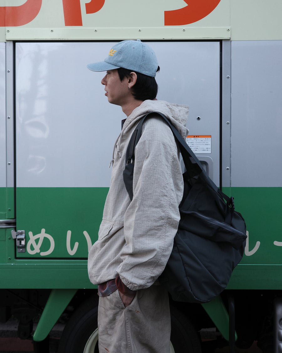 フード口のボタンの開閉により、首周りのニュアンスを自在に調整できる一着。素材には、麻カスや節を活かしたネップ糸を織り交ぜたコットンリネンチェックを採用しました。ドライタッチな生地にワンウォッシュを施すことで、麻特有のハリ感を残しつつ、肌馴染みの良い柔らかな風合いと豊かな表情を引き出しています。

This piece features adjustable hood buttons to alternate between a clean look and a relaxed neckline. Crafted from a cotton-linen check weave with rustic nep yarns, it highlights the natural texture of the fibers. The BEIGE fabric is one-washed to balance a crisp, dry touch with a soft, broken-in feel, creating a sophisticated yet comfortable aesthetic.