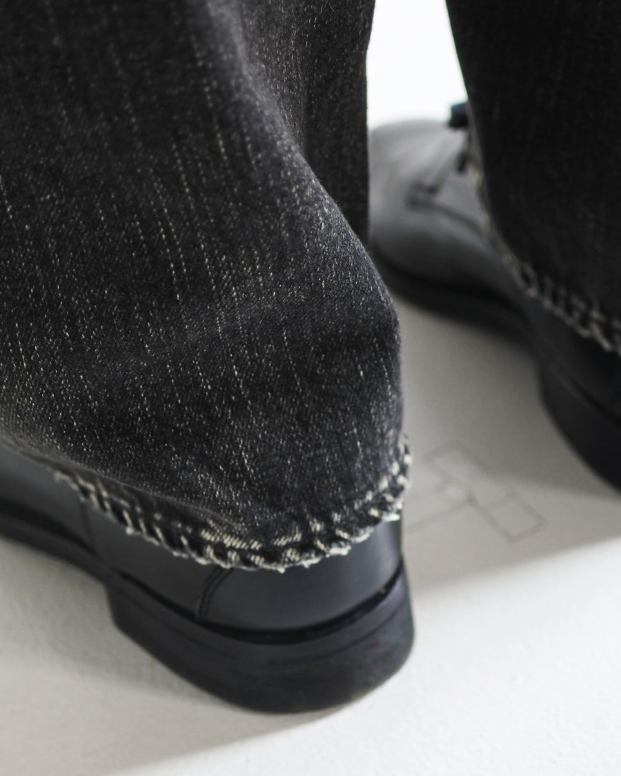 ANACHRONORM定番のレギュラーテーパード5Pパンツをベースに、リメイクで再構築した一本。
腰回りにはゆとりを持たせつつ、裾へ向かってすっきりと収まる美しいテーパードシルエットが特徴です。
タテ糸は硫化ロープ染色を施した芯白仕様で、ブラックからグレーへ自然にフェードする豊かな経年変化が魅力。
ムラ糸が生み出す自然な陰影により、ヴィンテージライクな表情を楽しめます。
さらにタテヨコに硫化ブラックのスラブ糸を使用し、ベーストーンを抑えながらもアタリを際立たせた奥行きのあるコントラストを表現。
リアルなユーズド感を備えた、加工映えする一本に仕上げています。
A reconstructed take on ANACHRONORM’s classic Regular Tapered 5P Pants, refined through its remake design.
The fit offers room around the waist with a clean taper toward the hem, ensuring both comfort and sharp lines.
Warp yarns a