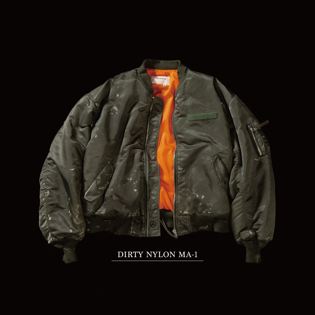 忠実なディテールを保ちながら、シルエットを現代的に整えたMA-1ジャケット。加工によりヴィンテージの風合いを再現した一着です。肉厚でミリタリーらしいツイル生地を使用し、打ち込みの密度や肌触りまでビンテージMA-1に近い仕上がりに。さらに、ダートペイントや特殊吹き付け、ダメージ加工を重ね、洗いをかけて染料を自然に剥がすことで、深みのある表情を生み出しています。カラーはオリーブ。