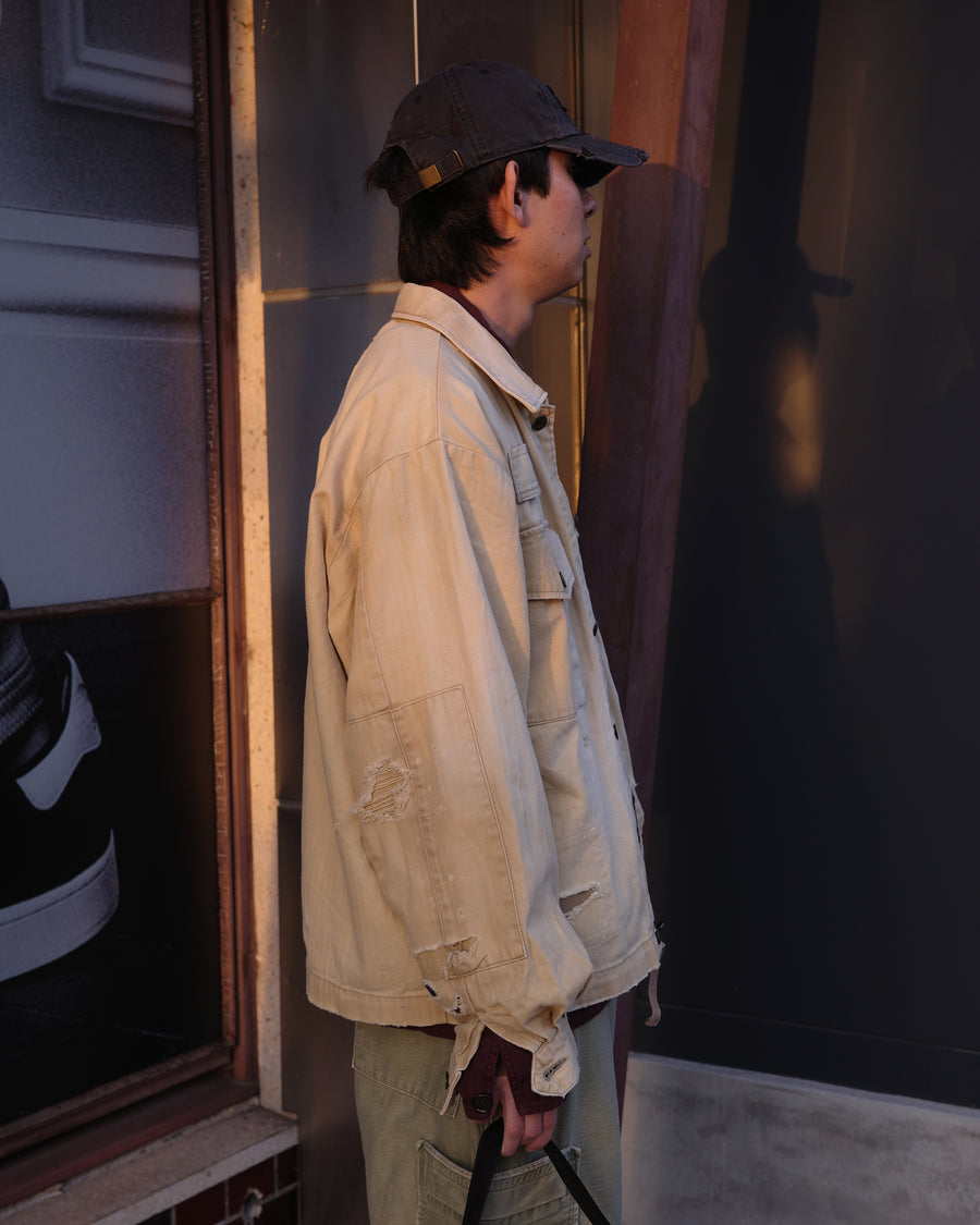ミリタリーのシャツジャケットを現代的シルエットに更新。裾のドローコードでスタイルに合わせた変化を楽しめます。素材には肌馴染みの良い10sヘリンボンを採用。環境に配慮した特殊エイジング・サンフェード加工とダメージ加工を施すことで、クラシカルな生地にリアリティのある褪色感とヴィンテージライクな佇まいを表現しました。

A modern military shirt jacket with hem drawcords for an adjustable silhouette. Crafted from soft 10s herringbone, this KHAKI piece undergoes a special sun-fade and damage process. It achieves a realistic, time-worn vintage look with authentic distressing while minimizing environmental impact through eco-conscious processing.