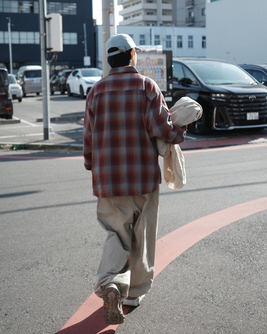 オンブレチェック柄が目を惹くオープンカラーシャツ。生地が持つ自然なドレープ感を活かし、リラックス感のあるゆとりを持たせたシルエットに仕上げました。素材にはタテ・ヨコ共にレーヨン糸を使用したレーヨンチェックを採用。非常に優れた落ち感と、袖を通した瞬間に感じる滑らかで心地よい肌触りが、上質なリラックススタイルを演出します。

An open-collar shirt featuring a classic ombre check pattern. The relaxed silhouette highlights the natural drape and fluid movement of the fabric. Crafted from a high-quality rayon check weave, this RED CHECK piece is characterized by its exceptional softness and smooth touch, offering a sophisticated look with an effortlessly comfortable feel.