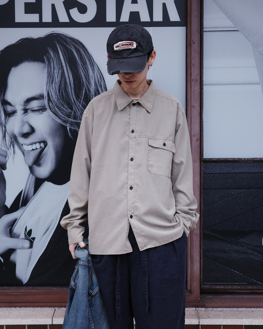 ポリエステル100％ながら、綿のような質感と軽量性を備えた高機能素材を採用。タスラン加工糸を使用したポリエステルオックスは、シワになりにくく速乾性にも優れています。本来染色が困難な素材に特殊顔料染めを施すことで、化繊特有の光沢を抑え、ナチュラルで奥行きのある絶妙なフェード感と落ち着いた表情を実現しました。

A high-performance piece crafted from polyester oxford, offering a cotton-like touch with quick-dry and wrinkle-resistant benefits. This GRAY BEIGE item features a special pigment dye—a rare process for polyester—achieving a sophisticated, faded texture and a matte finish that perfectly balances technical utility with a natural, lived-in aesthetic.