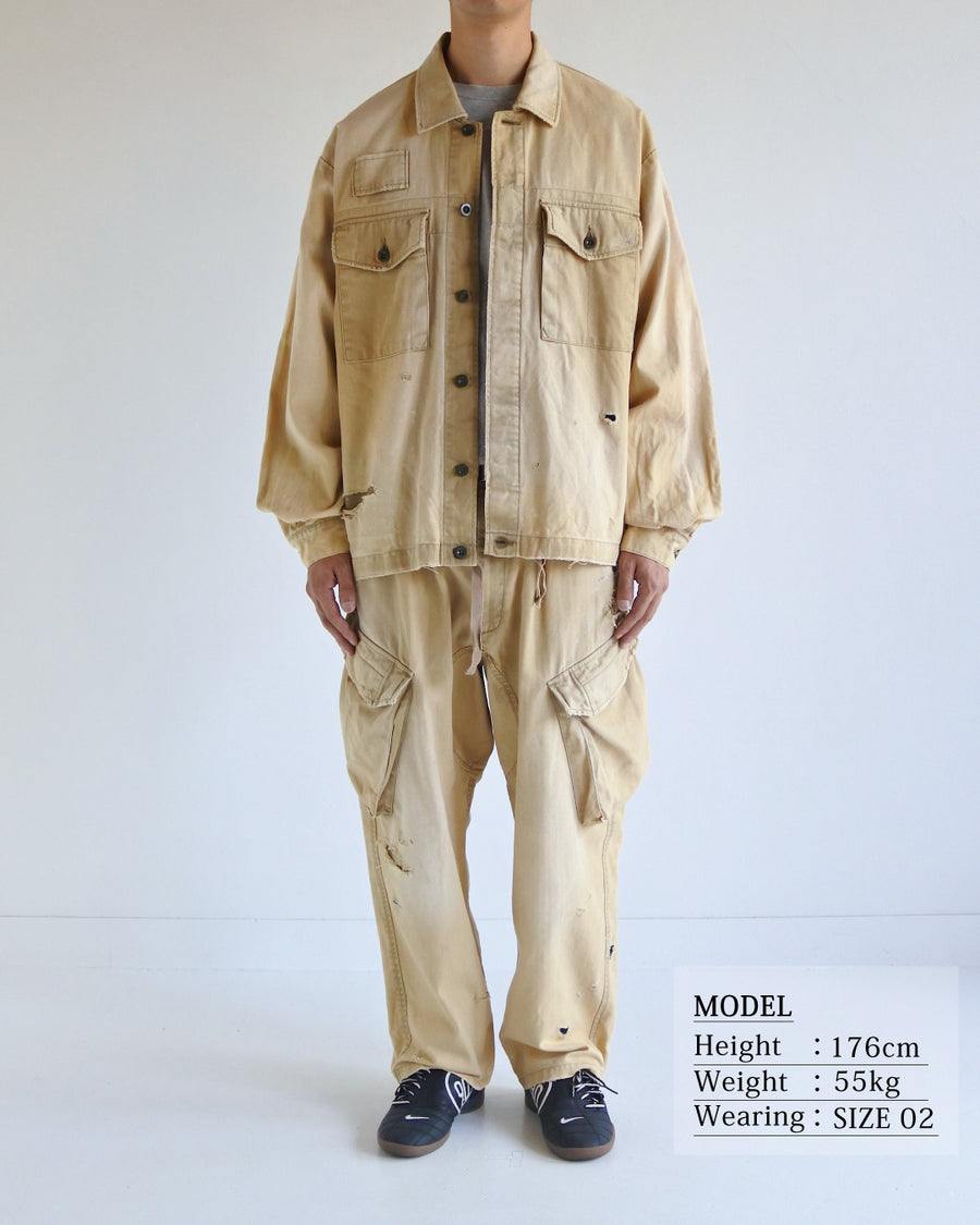 ミリタリーのシャツジャケットを現代的シルエットに更新。裾のドローコードでスタイルに合わせた変化を楽しめます。素材には肌馴染みの良い10sヘリンボンを採用。環境に配慮した特殊エイジング・サンフェード加工とダメージ加工を施すことで、クラシカルな生地にリアリティのある褪色感とヴィンテージライクな佇まいを表現しました。

A modern military shirt jacket with hem drawcords for an adjustable silhouette. Crafted from soft 10s herringbone, this KHAKI piece undergoes a special sun-fade and damage process. It achieves a realistic, time-worn vintage look with authentic distressing while minimizing environmental impact through eco-conscious processing.