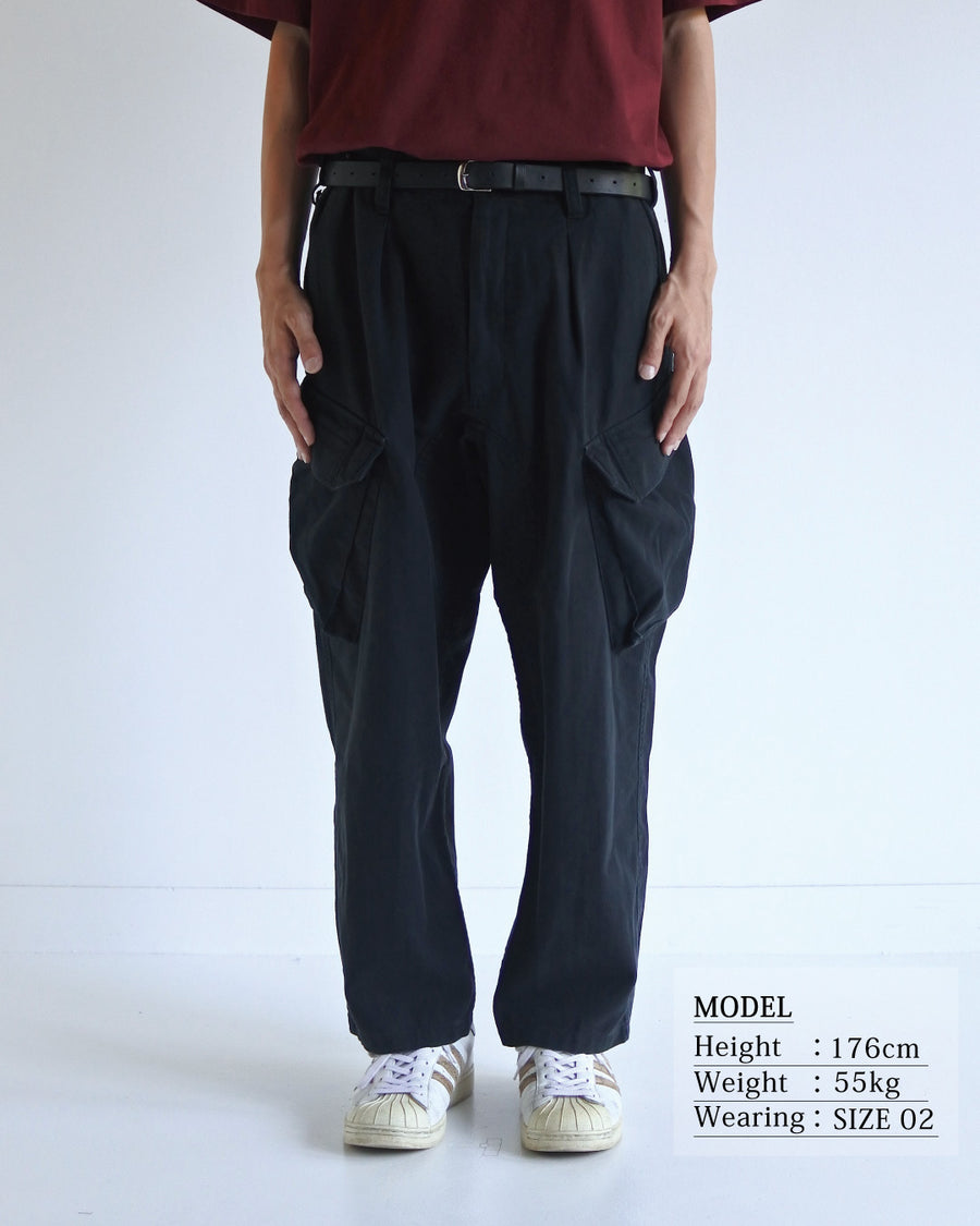 ミリタリートラウザーズをベースに、シルエットを現代的にリファイン。印象的な斜めのカーゴポケットが、立体感と実用性を両立させています。裾にかけて緩やかに絞られたテーパードラインにより、無骨ながらも洗練された印象に。素材には肌馴染みの良い10sヘリンボンを採用し、ストーンバイオウォッシュで柔らかな風合いとこなれ感を引き出しました。

Military trousers refined with a modern tapered silhouette. The distinctive slanted cargo pockets offer both practical utility and a structured look. Crafted from soft, classic 10s herringbone, this BLACK pair has been treated with a stone bio-wash, providing a comfortable, worn-in texture and a sophisticated take on rugged style.