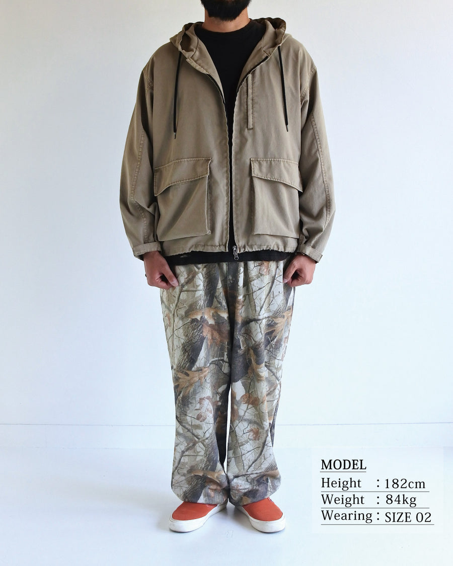 ポリエステル100％でありながら、綿のような質感と軽量性を備えた高機能な一着。タスラン加工糸を使用したポリエステルオックスを採用し、シワになりにくく速乾性に優れたイージーケア性を実現しました。本来染色が困難な素材に特殊顔料染めを施すことで、化繊特有の光沢を抑えた、ナチュラルで奥行きのある絶妙なフェード感を表現しています。

A high-performance piece crafted from polyester oxford, offering a cotton-like touch with lightweight, quick-dry, and wrinkle-resistant properties. This GRAY BEIGE item features a special pigment dye—a rare process for polyester—achieving a sophisticated, faded texture and a matte finish that defies its synthetic origins.