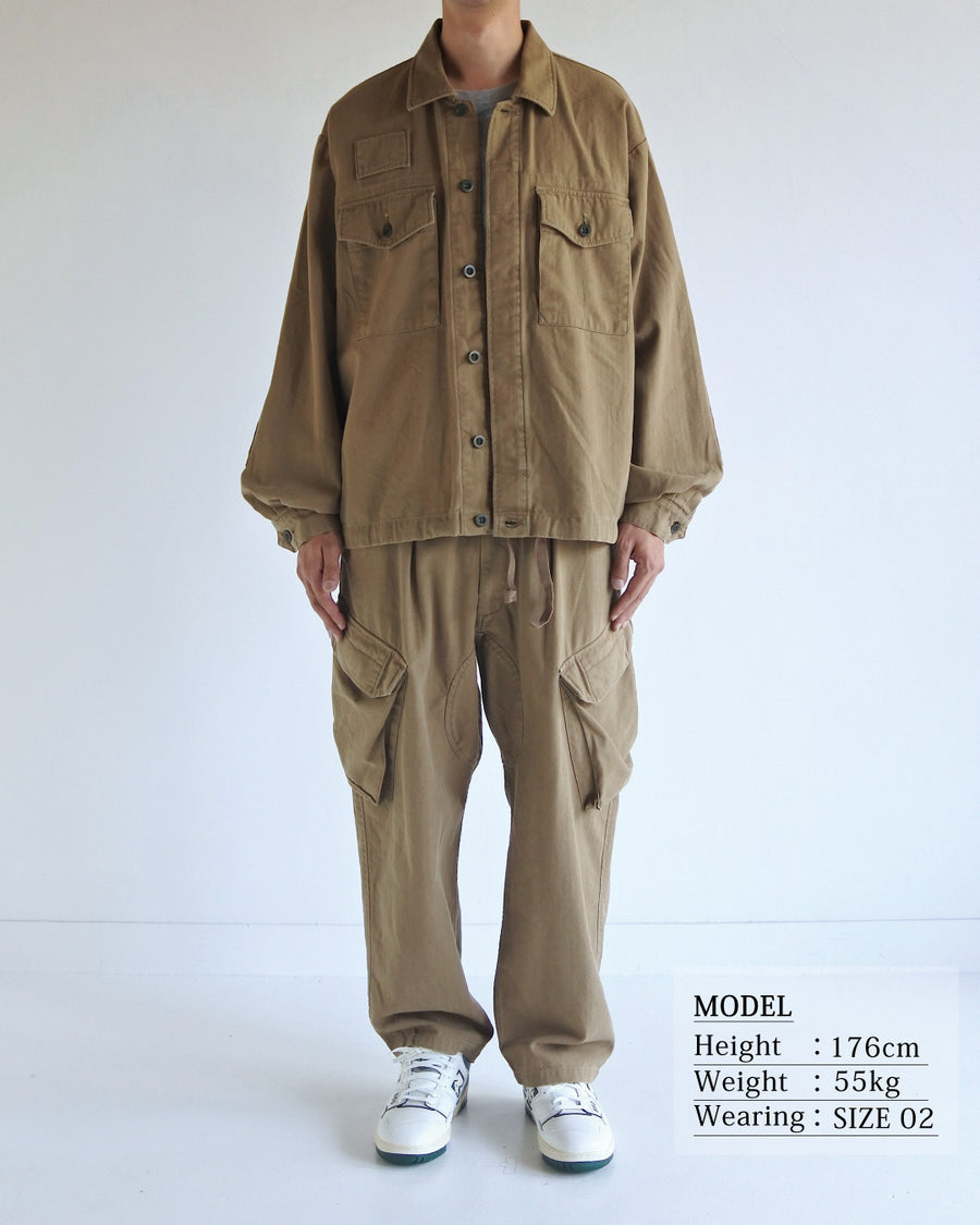 ミリタリーのシャツジャケットを現代的シルエットに更新。裾のドローコードで着丈のニュアンスを自在に調整可能です。素材には、やや甘織りで肌馴染みの良い10sヘリンボンを採用。ストーンバイオウォッシュを施すことで、クラシカルな生地感に柔らかな風合いとこなれ感をプラスした、着回し力の高い一着に仕上げました。

A modern update to the classic military shirt jacket, featuring hem drawcords for an adjustable silhouette. Crafted from 10s herringbone, slightly loose-knitted for a soft, comfortable touch. This KHAKI piece has been treated with a stone bio-wash, giving the traditional weave a natural, worn-in texture and a sophisticated casual feel.