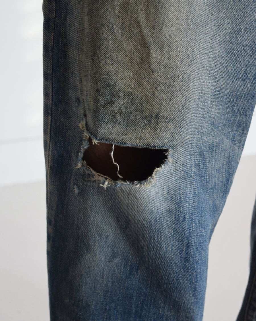 1985年のLEVIS 550をベースに再構築した、ワイドテーパードのリメイク5Pデニム。
12.5ozデニムのタテ糸には中白のインディゴロープ染色糸を使用し、ムラ感のある豊かな表情を演出。タテ落ちとインディゴの濃淡を活かすことで、ヴィンテージにはない独自の風合いを表現しています。さらに手作業のトーンコントロールと特別なエイジング加工を加えることで奥行きある仕上がりに。オリジナル染料の吹き付けにより、モダンでソリッドな印象も併せ持つ一本です。This remade 5P denim features a wide tapered silhouette inspired by the 1985 LEVIS 550.
The 12.5oz denim uses medium-white indigo rope–dyed warp yarns, giving it a textured, slubby character.
By highlighting vertical fading and vivid indigo variations, it achieves a look distinct from vin