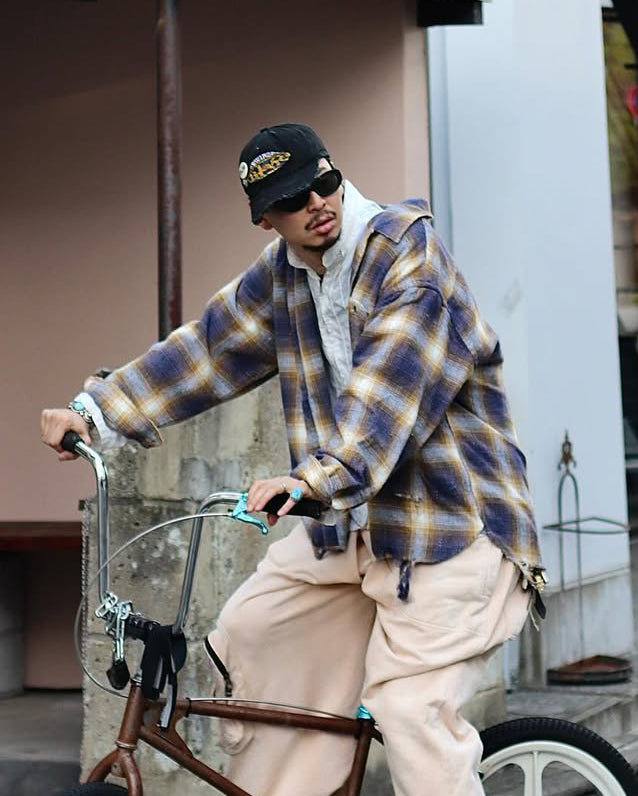 ANACHRONORMで以前リリースしていたリサイズシャツのシルエットをリファインした、ワイドシルエットシャツです。
随所に施された細かなステッチワークやダメージ加工にもご注目ください。
生地はリサイクルコットンとポリエステルを混紡したT/Cネップチェックで、起毛によるネップの風合いとメランジ染めの独特なムラ感が特徴です。
使用している生地はバランス別注でパープルとイエローのチェック柄。
サスティナブルブリーチ加工とダメージ加工を施しており、環境に配慮しつつPURPLE×BLACKカラーで仕上げています。