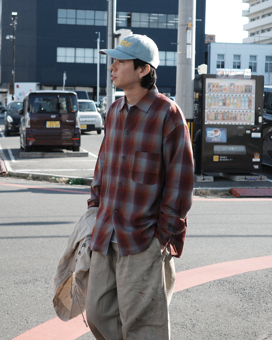 オンブレチェック柄が目を惹くオープンカラーシャツ。生地が持つ自然なドレープ感を活かし、リラックス感のあるゆとりを持たせたシルエットに仕上げました。素材にはタテ・ヨコ共にレーヨン糸を使用したレーヨンチェックを採用。非常に優れた落ち感と、袖を通した瞬間に感じる滑らかで心地よい肌触りが、上質なリラックススタイルを演出します。

An open-collar shirt featuring a classic ombre check pattern. The relaxed silhouette highlights the natural drape and fluid movement of the fabric. Crafted from a high-quality rayon check weave, this RED CHECK piece is characterized by its exceptional softness and smooth touch, offering a sophisticated look with an effortlessly comfortable feel.