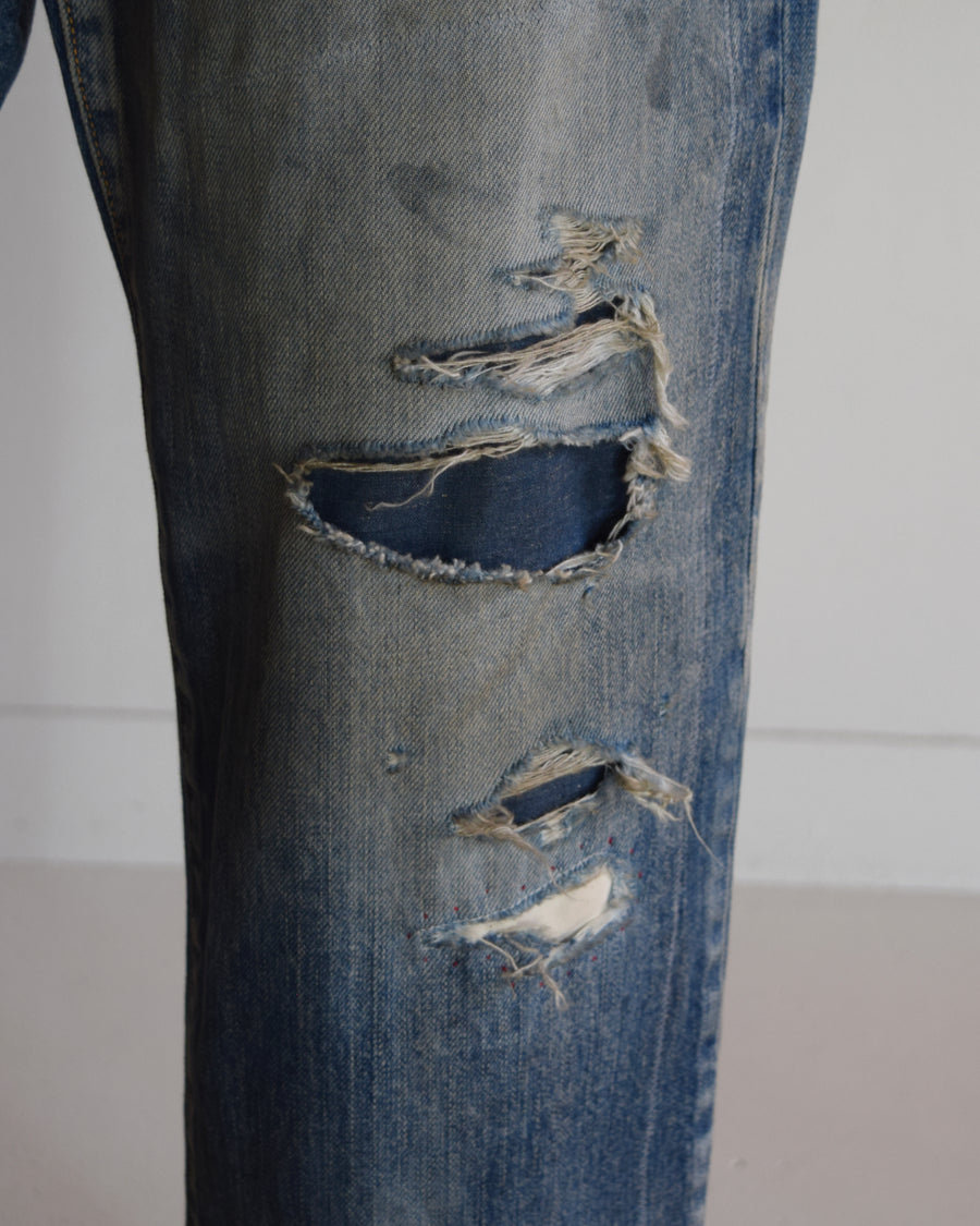 1985年のLEVIS 550をベースに再構築した、ワイドテーパードのリメイク5Pデニム。
12.5ozデニムのタテ糸には中白のインディゴロープ染色糸を使用し、ムラ感のある豊かな表情を演出。タテ落ちとインディゴの濃淡を活かすことで、ヴィンテージにはない独自の風合いを表現しています。さらに手作業のトーンコントロールと特別なエイジング加工を加えることで奥行きある仕上がりに。オリジナル染料の吹き付けにより、モダンでソリッドな印象も併せ持つ一本です。This remade 5P denim features a wide tapered silhouette inspired by the 1985 LEVIS 550.
The 12.5oz denim uses medium-white indigo rope–dyed warp yarns, giving it a textured, slubby character.
By highlighting vertical fading and vivid indigo variations, it achieves a look distinct from vin