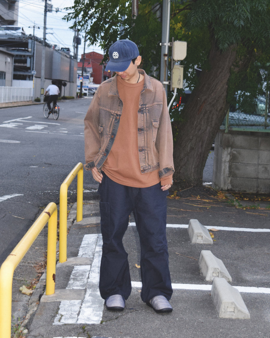 フラップポケットや膝のタック、裾のドローコードなど、ミリタリーディテールを随所に取り入れた1本。通常は内側に配置されるポケットをあえて外側に設けたカーゴポケットが印象的です。ムラ糸で織り上げたバックサテン生地は、独特のハリとコシを持ち、深みのあるネイビーカラーが魅力です。