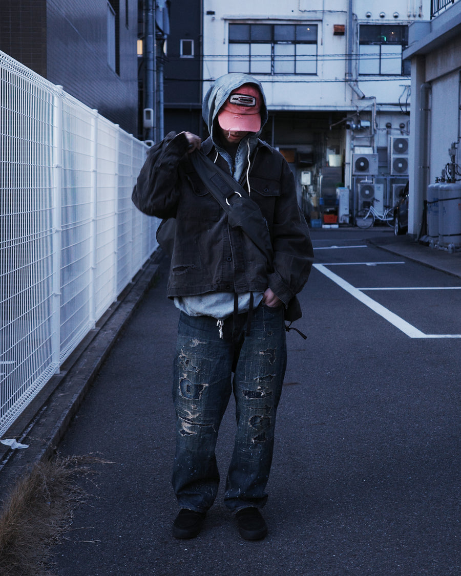 ミリタリーのシャツジャケットを現代的シルエットに更新。裾のドローコードでスタイルに合わせた変化を楽しめます。素材には肌馴染みの良い10sヘリンボンを採用。環境に配慮した特殊エイジング・サンフェード加工とダメージ加工を施すことで、クラシカルな生地にリアリティのある褪色感とヴィンテージライクな佇まいを表現しました。

A modern military shirt jacket with hem drawcords for an adjustable silhouette. Crafted from soft 10s herringbone, this BLACK piece undergoes a special sun-fade and damage process. It achieves a realistic, time-worn vintage look with authentic distressing while minimizing environmental impact through eco-conscious processing.