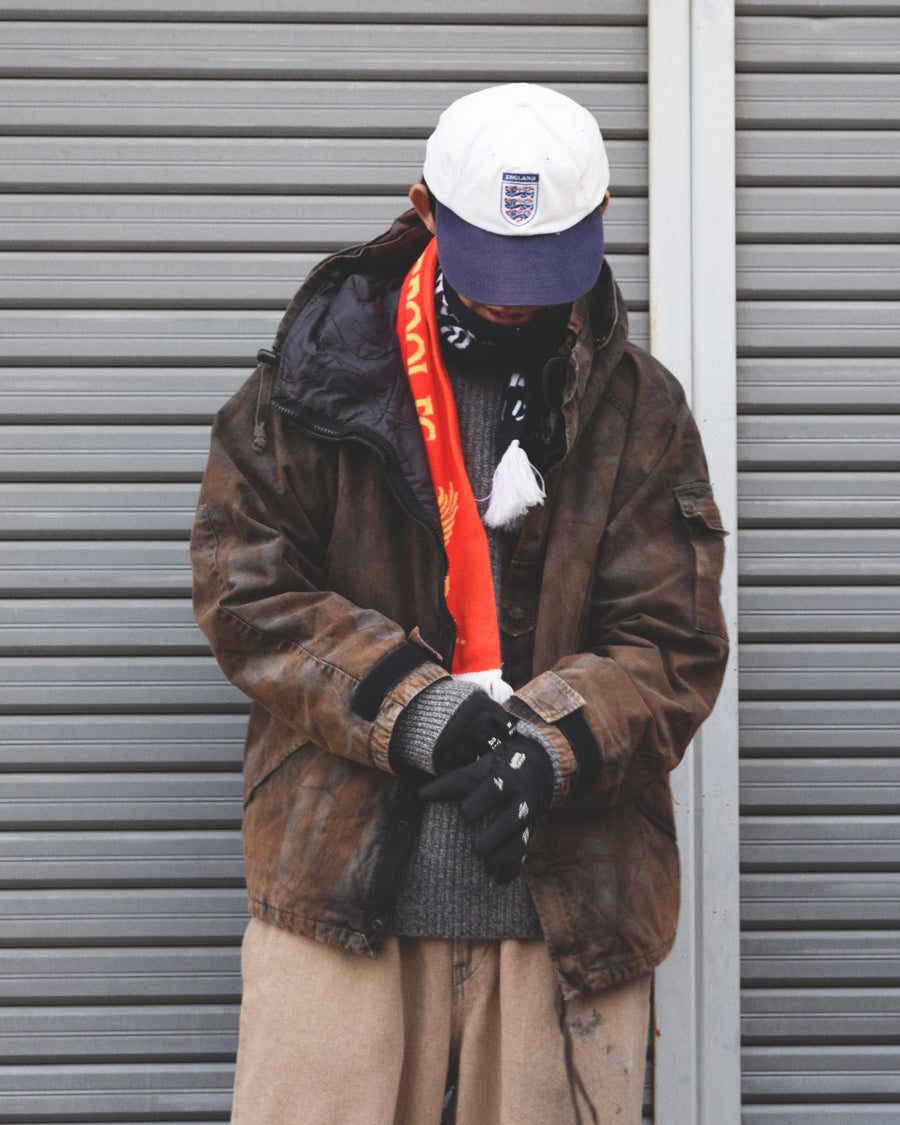 U.S. ARMYのフィールドジャケットをベースに再構築したパーカー。
中綿キルティングを採用し、重すぎず長いシーズン着用可能。
表地はパラフィンコーティングによる軽い撥水性を備えています。
20/リップストップ生地は裂けにくく、マットでしなやかな質感が特徴。
硫化染め後、水を一切使わないサステナブルブリーチを施した特別加工。
独特の風合いと環境配慮を両立した一着です。
A refined take on the U.S. Army field jacket silhouette.
Medium-weight quilted padding offers seasonal versatility without excess bulk.
The paraffin-coated shell provides light water repellency.
Crafted from durable 20/ripstop with a matte, supple texture.
Finished with sulfide dye and a fully water-free sustainable bleachi