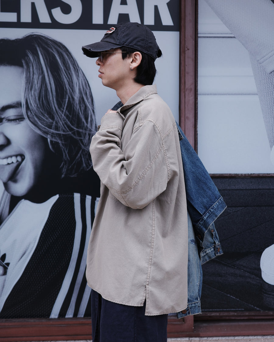 ポリエステル100％ながら、綿のような質感と軽量性を備えた高機能素材を採用。タスラン加工糸を使用したポリエステルオックスは、シワになりにくく速乾性にも優れています。本来染色が困難な素材に特殊顔料染めを施すことで、化繊特有の光沢を抑え、ナチュラルで奥行きのある絶妙なフェード感と落ち着いた表情を実現しました。

A high-performance piece crafted from polyester oxford, offering a cotton-like touch with quick-dry and wrinkle-resistant benefits. This GRAY BEIGE item features a special pigment dye—a rare process for polyester—achieving a sophisticated, faded texture and a matte finish that perfectly balances technical utility with a natural, lived-in aesthetic.