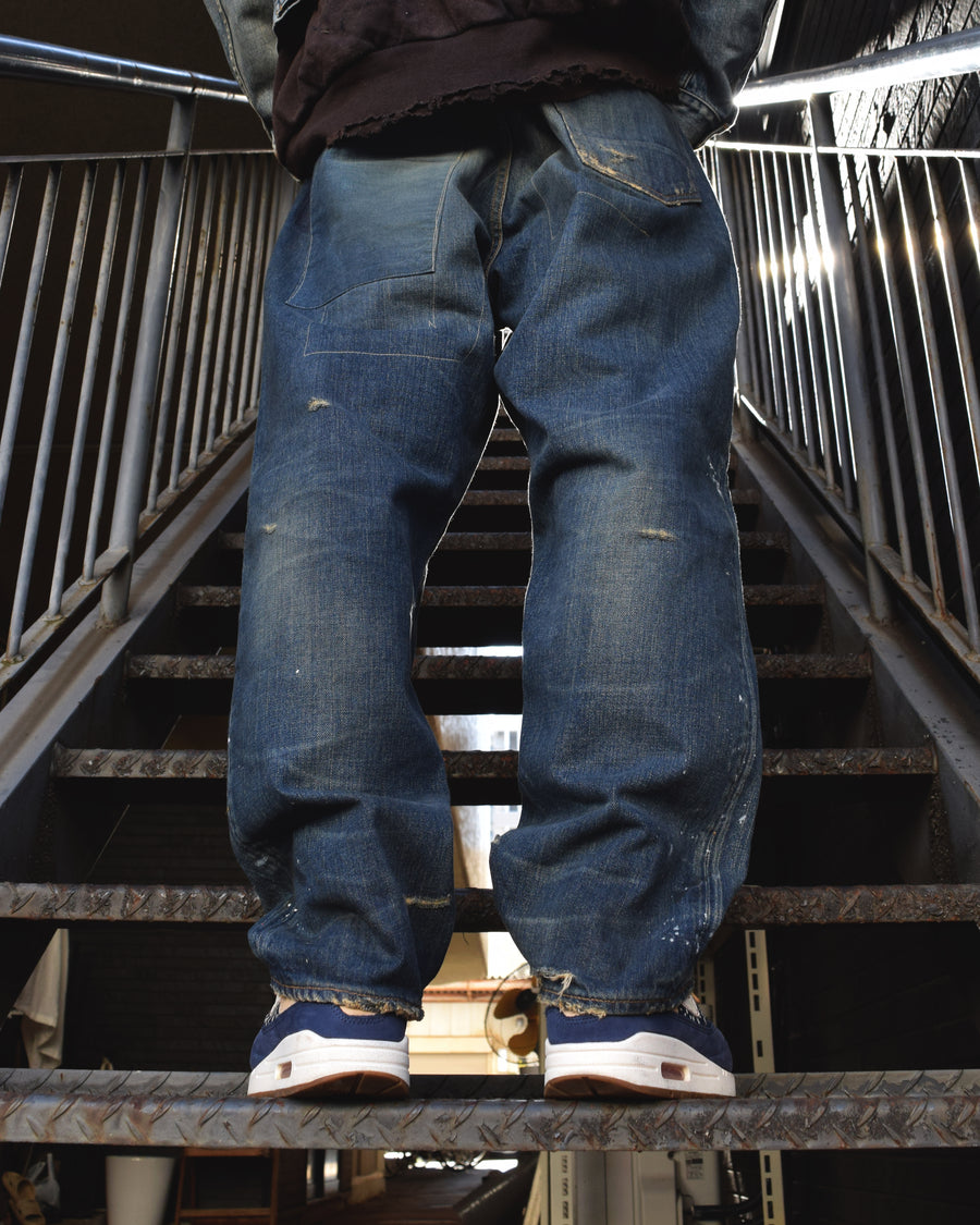 12.5ozデニムを使用したテーパードシルエット。
濃色エイジングとブリーチを組み合わせたハードダメージ加工。
複数の当て布でパッチワークリメイクを施した存在感ある一本です。
A tapered silhouette crafted from 12.5oz denim.
Features heavy damage with dark aging and bleach treatments.
Finished with patchwork-style remake details using multiple fabric patches.