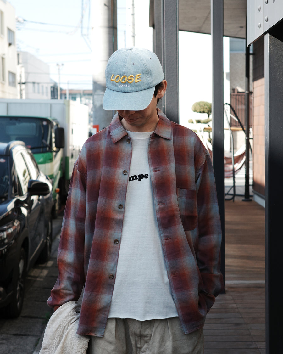 オンブレチェック柄が目を惹くオープンカラーシャツ。生地が持つ自然なドレープ感を活かし、リラックス感のあるゆとりを持たせたシルエットに仕上げました。素材にはタテ・ヨコ共にレーヨン糸を使用したレーヨンチェックを採用。非常に優れた落ち感と、袖を通した瞬間に感じる滑らかで心地よい肌触りが、上質なリラックススタイルを演出します。

An open-collar shirt featuring a classic ombre check pattern. The relaxed silhouette highlights the natural drape and fluid movement of the fabric. Crafted from a high-quality rayon check weave, this RED CHECK piece is characterized by its exceptional softness and smooth touch, offering a sophisticated look with an effortlessly comfortable feel.
