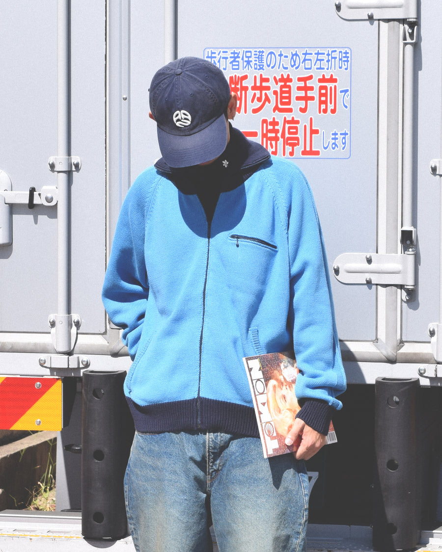 コットンニットを使用したドライバーズニット。
太番手の強撚糸による特殊な天竺編みで、適度なハリと風合いを持たせています。
ゆとりのある身幅ながら、アウターのインナーとしても使いやすいバランスの取れたシルエットに仕上げました。コットン素材のためホームクリーニングも可能です。
カラーは鮮やかなスカイブルー。