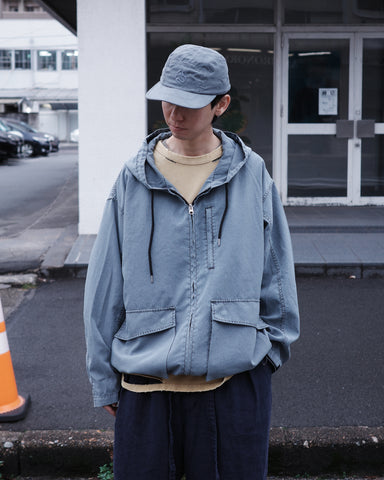 ポリエステル100％でありながら、綿のような質感と軽量性を備えた高機能な一着。タスラン加工糸を使用したポリエステルオックスを採用し、シワになりにくく速乾性に優れたイージーケア性を実現しました。本来染色が困難な素材に特殊顔料染めを施すことで、化繊特有の光沢を抑えた、ナチュラルで奥行きのある絶妙なフェード感を表現しています。

A high-performance piece crafted from polyester oxford, offering a cotton-like touch with lightweight, quick-dry, and wrinkle-resistant properties. This GRAY BLUE item features a special pigment dye—a rare process for polyester—achieving a sophisticated, faded texture and a matte finish that defies its synthetic origins.