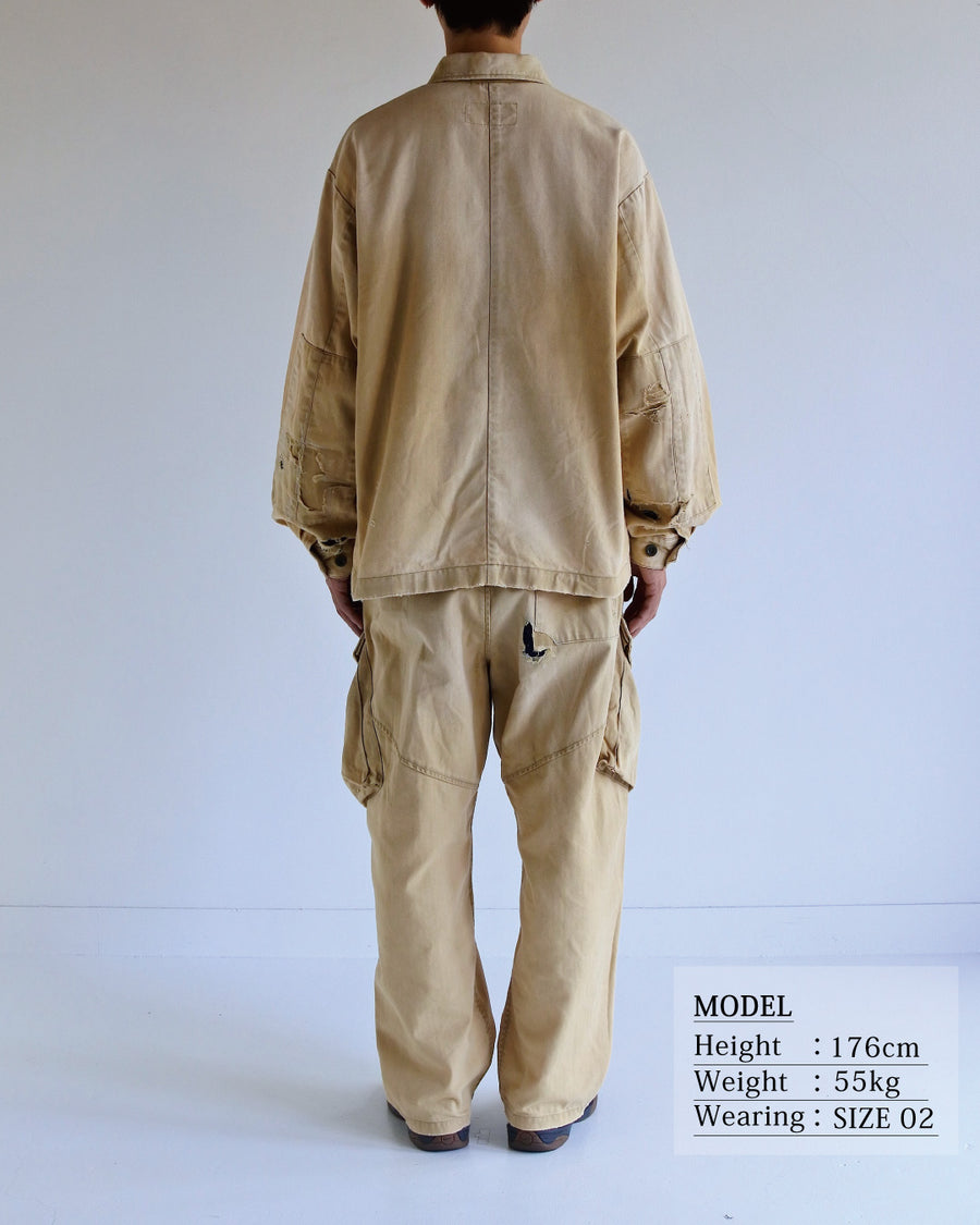 ミリタリーのシャツジャケットを現代的シルエットに更新。裾のドローコードでスタイルに合わせた変化を楽しめます。素材には肌馴染みの良い10sヘリンボンを採用。環境に配慮した特殊エイジング・サンフェード加工とダメージ加工を施すことで、クラシカルな生地にリアリティのある褪色感とヴィンテージライクな佇まいを表現しました。

A modern military shirt jacket with hem drawcords for an adjustable silhouette. Crafted from soft 10s herringbone, this KHAKI piece undergoes a special sun-fade and damage process. It achieves a realistic, time-worn vintage look with authentic distressing while minimizing environmental impact through eco-conscious processing.