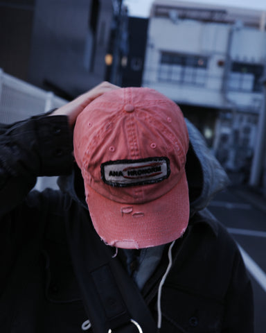 ダメージ加工とステッチ補強で、長年使い込まれた風合いを表現したキャップ。オリジナルワッペンにも同様の加工を施し、全体の統一感を高めました。素材には先染めのピグメントコットンキャンバスを採用。実用性とヴィンテージな佇まいを兼ね備え、スタイリングにこなれたアクセントを添える一着に仕上げています。

A distressed cap featuring reinforced stitching for a rugged, time-worn look. Both the body and the original patch are meticulously aged for a cohesive vintage aesthetic. Crafted from pre-dyed pigment cotton canvas, this RED piece combines durability with a sophisticated, lived-in feel, perfect for adding character to any outfit.