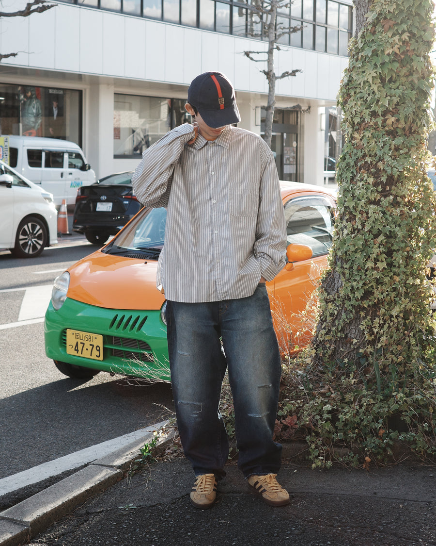 クリーンな高密度ストライプシャツに、スプレーによる顔料吹き付け加工を施し、自然なムラ感を与えた一着。リラックス感のあるシルエットが、上品さとラフさを絶妙なバランスで両立させています。素材には米綿100%の高密度ストライプ生地を採用。綿100%のナチュラルな風合いながら、シワになりにくい実用性も兼ね備えています。

A clean stripe shirt enhanced with a subtle pigment spray process for a natural, textured look. The relaxed silhouette perfectly balances elegance with a casual edge. Crafted from high-density US cotton stripe fabric, this WHITE STRIPE piece offers a crisp feel that is naturally wrinkle-resistant while maintaining the comfort of 100% cotton.