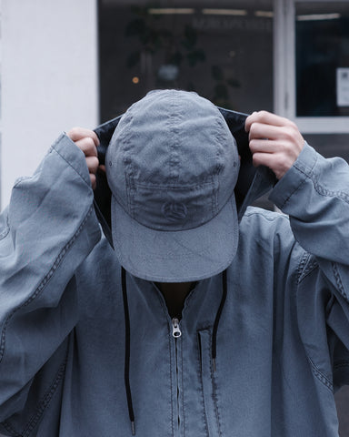 綿のような質感と軽量性を備えた高機能なポリエステルオックスを採用。タスラン加工糸により、シワになりにくく速乾性に優れたイージーケア性を実現しました。染色が困難なポリエステルに特殊顔料染めを施すことで、光沢を抑えたナチュラルで奥行きのある表情に。裏地にはサステナブルなリサイクルメッシュを使用し、快適な着用感にもこだわりました。

High-performance polyester oxford with a cotton-like touch, offering quick-dry and wrinkle-resistant benefits. This GRAY BLUE piece features a special pigment dye for a matte, faded texture, defying its synthetic roots. Lined with eco-friendly recycled mesh, it ensures breathability while maintaining a sophisticated, natural aesthetic.