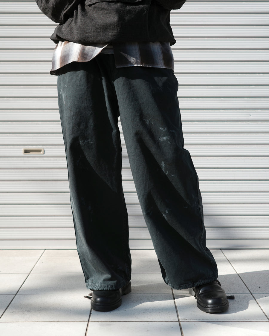 フロントに2タックを施し、ワタリから裾にかけてゆとりを持たせたワイルドなワイドシルエット。裾のドローコードでシルエットの変化も自在に楽しめます。素材には耐久性に優れ、綾織特有の柔らかさを持つ厚手チノクロスを採用。ストーンバイオウォッシュと汚し加工を重ねることで、長年穿き込んだようなリアルな質感と深みのある表情を引き出しました。

Wild, wide-silhouette pants with double-tucked fronts and adjustable hem drawcords. Crafted from durable, soft chino cloth, this CHARCOAL pair features a stone bio-wash and staining process. This creates an authentic, rugged texture and a deeply weathered look, blending vintage workwear aesthetics with a modern, voluminous fit.