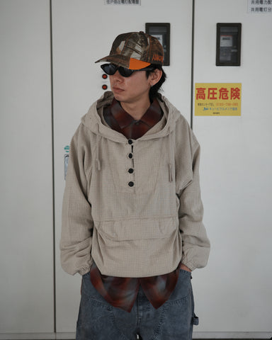 フード口のボタンの開閉により、首周りのニュアンスを自在に調整できる一着。素材には、麻カスや節を活かしたネップ糸を織り交ぜたコットンリネンチェックを採用しました。ドライタッチな生地にワンウォッシュを施すことで、麻特有のハリ感を残しつつ、肌馴染みの良い柔らかな風合いと豊かな表情を引き出しています。

This piece features adjustable hood buttons to alternate between a clean look and a relaxed neckline. Crafted from a cotton-linen check weave with rustic nep yarns, it highlights the natural texture of the fibers. The BEIGE fabric is one-washed to balance a crisp, dry touch with a soft, broken-in feel, creating a sophisticated yet comfortable aesthetic.