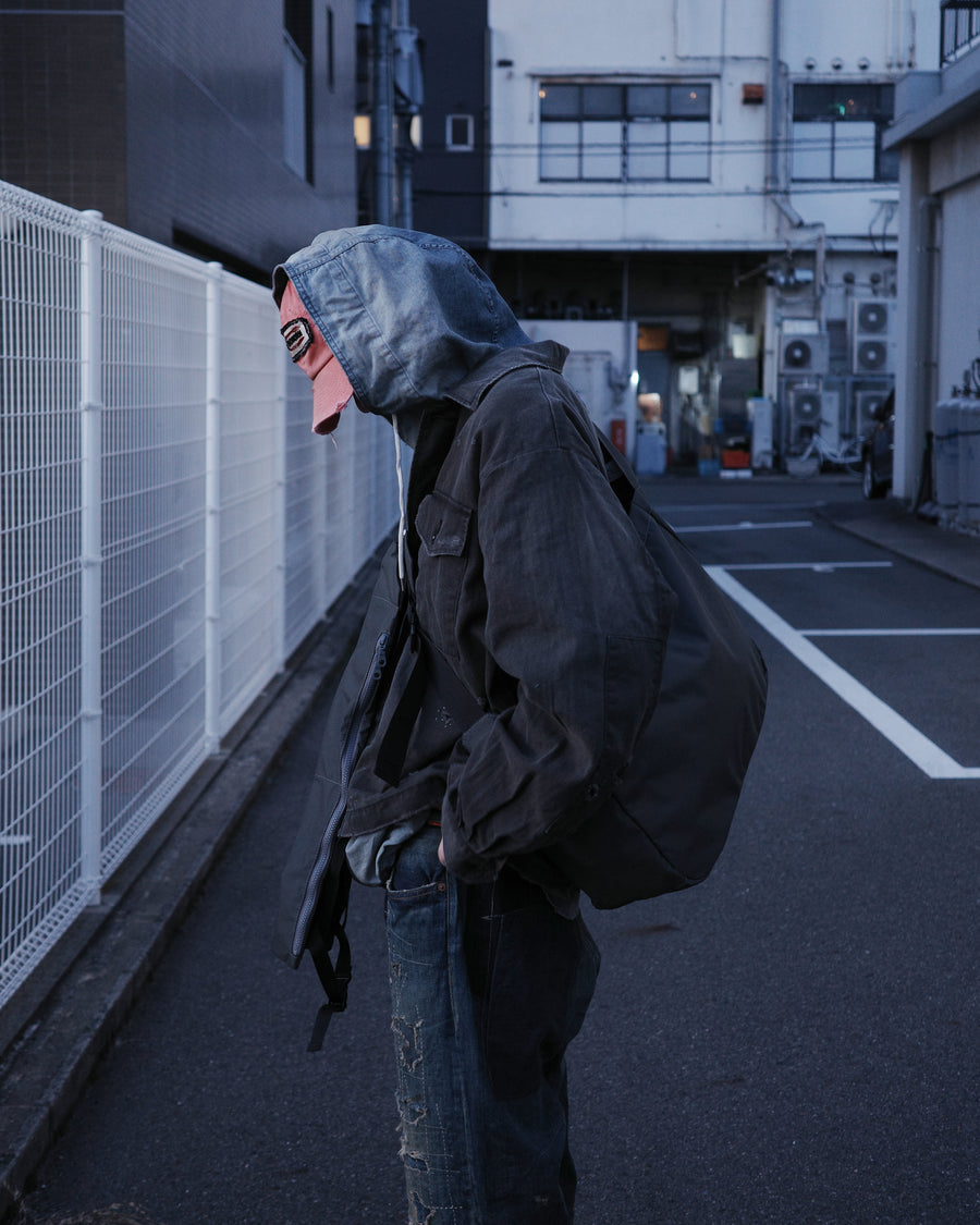 ミリタリーのシャツジャケットを現代的シルエットに更新。裾のドローコードでスタイルに合わせた変化を楽しめます。素材には肌馴染みの良い10sヘリンボンを採用。環境に配慮した特殊エイジング・サンフェード加工とダメージ加工を施すことで、クラシカルな生地にリアリティのある褪色感とヴィンテージライクな佇まいを表現しました。

A modern military shirt jacket with hem drawcords for an adjustable silhouette. Crafted from soft 10s herringbone, this BLACK piece undergoes a special sun-fade and damage process. It achieves a realistic, time-worn vintage look with authentic distressing while minimizing environmental impact through eco-conscious processing.