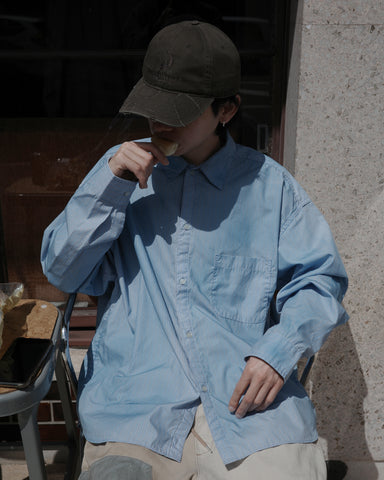 クリーンな高密度ストライプシャツに、スプレーによる顔料吹き付け加工を施し、自然なムラ感を与えた一着。リラックス感のあるシルエットが、上品さとラフさを絶妙なバランスで両立させています。素材には米綿100%の高密度ストライプ生地を採用。綿100%のナチュラルな風合いながら、シワになりにくい実用性も兼ね備えています。

A clean stripe shirt enhanced with a subtle pigment spray process for a natural, textured look. The relaxed silhouette perfectly balances elegance with a casual edge. Crafted from high-density US cotton stripe fabric, this BLUE STRIPE piece offers a crisp feel that is naturally wrinkle-resistant while maintaining the comfort of 100% cotton.